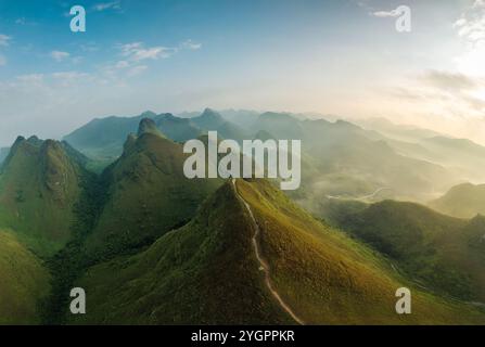 Vue aérienne de la belle colline d'herbe de Ba Guang, chaîne de montagnes avec brouillard et villageois apportant cheval à paître sur la montagne dans la matinée à Ha Lang, Banque D'Images