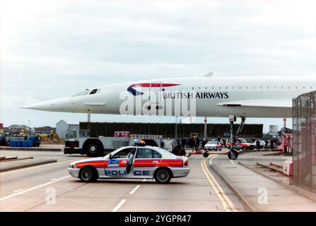 British Airways BAC Concorde G-BOAC est remorqué à travers Eastchurch Road à l'aéroport de Londres Heathrow, avec la route fermée par la police. La flotte de BA Concorde était stationnée dans son hangar de maintenance sur le périmètre de l'aéroport et remorquée dans la zone intérieure de l'aéroport lorsque nécessaire pour effectuer des vols réguliers. Des passionnés se sont rassemblés pour voir le Concorde vers la fin de son service nécessitant une plus grande présence policière. Il vola pour la première fois sous le nom de G-BOAC en 1975. Livré à British Airways en 1976. Il s'envole pour Manchester pour y être préservé et exposé le 31 octobre 2003 Banque D'Images