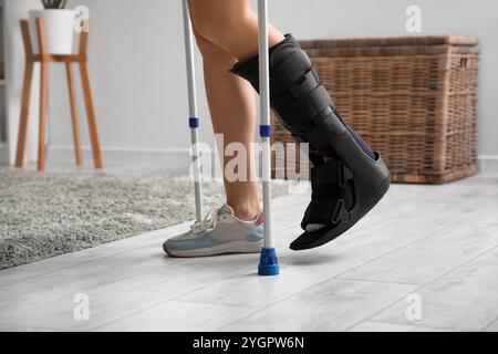 Jeune femme avec une jambe cassée et des béquilles marchant à la maison, gros plan Banque D'Images