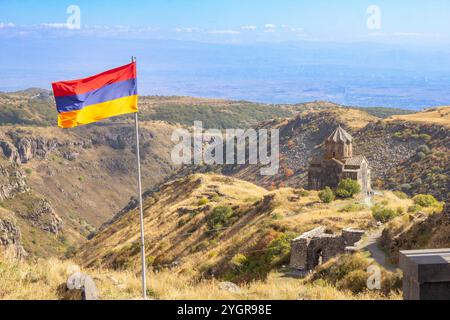 Vue aérienne de drone au drapeau de l'Arménie et célèbre église Vahramashen du 11ème siècle, près de la forteresse d'Amberd dans la journée ensoleillée d'été. Falaise avec Arkashian Banque D'Images