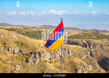 Vue aérienne de drone au drapeau de l'Arménie et célèbre église Vahramashen du 11ème siècle, près de la forteresse d'Amberd dans la journée ensoleillée d'été. Falaise avec Arkashian Banque D'Images