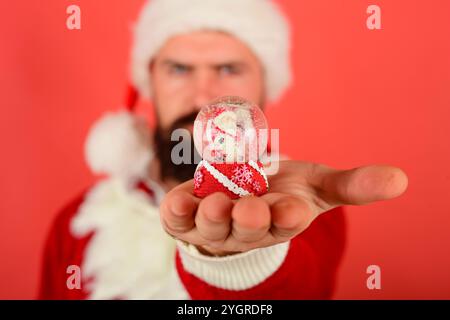 Décoration de Noël. Père Noël avec boule de neige de Noël sur la paume. Mise au point sélective. Père Noël barbu tient une boule de verre avec le petit père Noël et Ar Banque D'Images