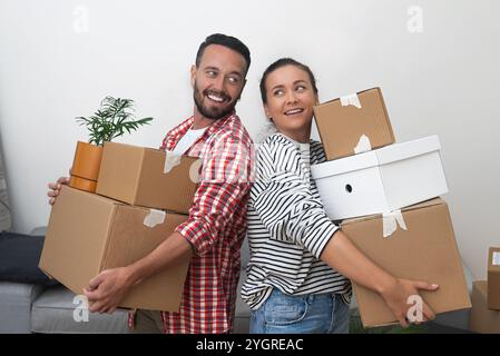 couple, louant un nouvel endroit, transporte des boîtes de déménagement en carton au salon, déterminé à s'installer Banque D'Images