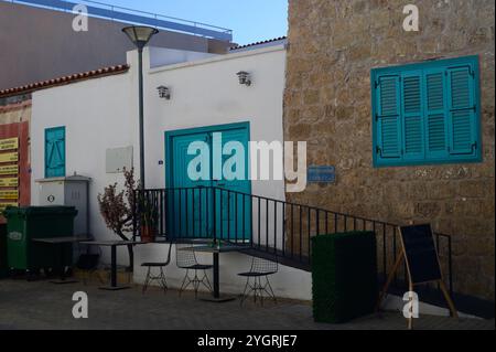 Un bâtiment pittoresque dispose de portes turquoises vibrantes, entouré de verdure et accueillant sièges extérieurs. Banque D'Images