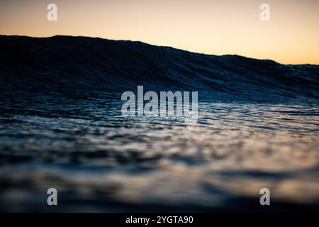Une douce vague se met en mouvement alors que le soleil se couche sur Waikiki Banque D'Images