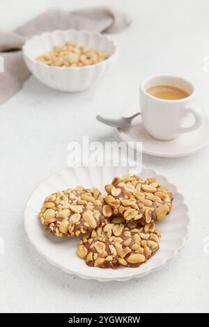 Un tas de biscuits portugais traditionnels aux arachides connus sous le nom de Bolachas de Amendoim sur la plaque blanche avec une tasse de café, une serviette et une assiette de cacahuètes sur Banque D'Images