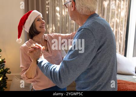 Danser joyeusement à la maison, couple senior célébrant Noël ensemble Banque D'Images