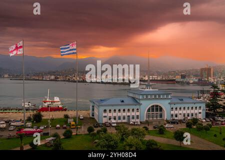 La vue sur le port maritime de Batoumi, Géorgie, avec le bâtiment du terminal portuaire, drapeaux de la Géorgie et de la République d'Adjara, pendant le beau coucher de soleil. Banque D'Images