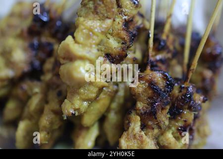 Succulent gros plan de poulet grillé satay sur bâtonnets de bambou, avec bords carbonisés et marinade riche. Banque D'Images