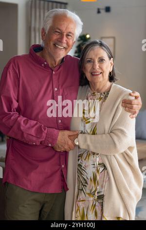 Heureux couple senior embrassant à la maison, célébrant Noël avec joie Banque D'Images