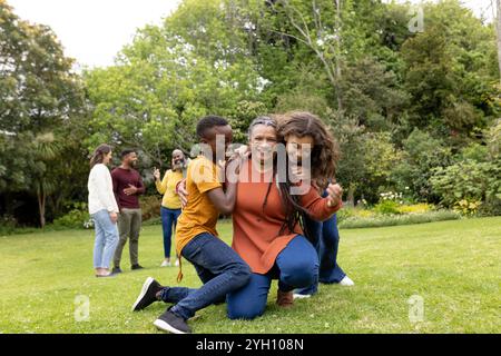 famille mutliracial profitant de moments ludiques ensemble dans le jardin ensoleillé, souriant et embrassant Banque D'Images