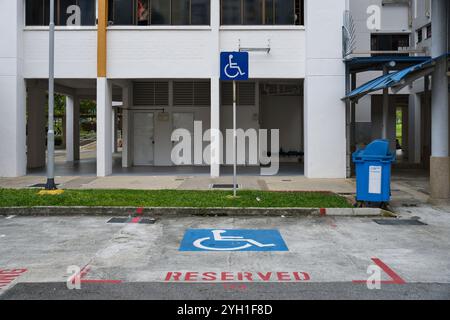 Place de parking réservée aux personnes handicapées dans un parking HDB à Singapour, avec marquage au sol et panneau pour les personnes handicapées. Banque D'Images