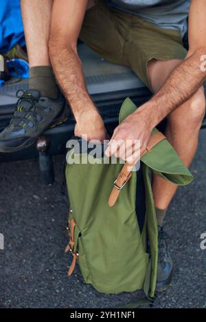 Sac à dos, mains et randonnée avec personne dans les montagnes, se préparer pour l'escalade ou voyage en gros plan. Sac, voiture et commencer avec randonneur extérieur d'en haut Banque D'Images