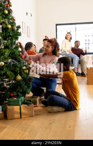 Décorer l'arbre de noël, famille multiraciale célébrant des vacances festives à la maison, à la maison Banque D'Images