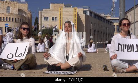 JÉRUSALEM - 8 NOVEMBRE : des militantes israéliennes de la paix vêtues de blanc s'assoient tranquillement en cercle avec des signes promouvant les valeurs de tolérance et de coexistence lors d'une manifestation de sit-in devant la vieille ville appelant à un cessez-le-feu et à une solution diplomatique à la guerre en cours à Gaza et au Liban le 8 novembre 2024 à Jérusalem. Israël Banque D'Images