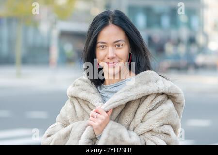 Portrait élégant d'une jeune femme de 20-25 ans, aspect oriental, avec panorama flou de la ville sur le fond. Banque D'Images