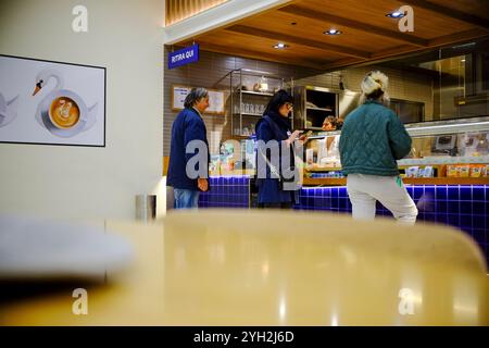 Traversetolo, Parme, Italie - 6 novembre 2024 les clients passent leurs commandes dans un comptoir de cafétéria lumineux et moderne avec des carreaux bleus et du bois Banque D'Images