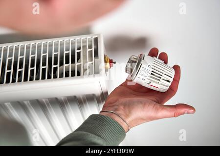 Bavière, Allemagne - 8 novembre 2024 : un homme démonte un thermostat de chauffage d'un radiateur. Image symbolique pour la réduction des coûts de chauffage, l'entretien et les ajustements en temps de crise énergétique *** Ein Mann demontiert ein Heizungsthermostat von einem Heizkörper. Symbolbild für Heizkostenreduktion, Wartung und Anpassungen in Zeiten der Energiekrise Banque D'Images