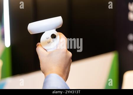 Un joystick de réalité virtuelle dans la main d'une personne, avec un arrière-plan flou autour. Banque D'Images