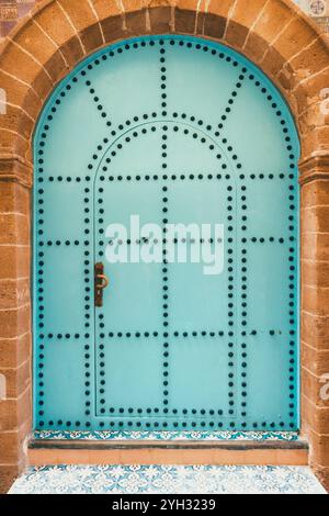 Porte extérieure bleue arquée marocaine décorative traditionnelle avec clous en métal noir ornés et étape complexe avec des détails géométriques de tuiles, gros plan, en o Banque D'Images