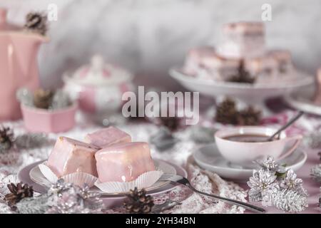 Gâteaux glacés roses, beignets de punch entourés de décorations d'hiver et d'une tasse à café Banque D'Images