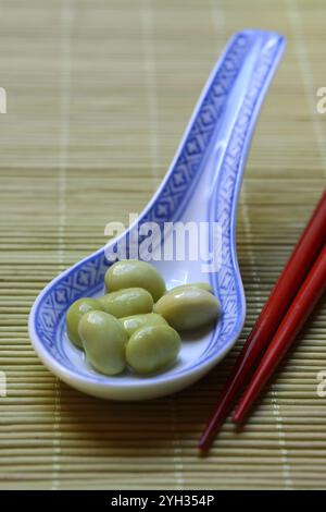 Edamame, fèves de soja non mûres dans une cuillère en céramique asiatique, Glycine max Banque D'Images