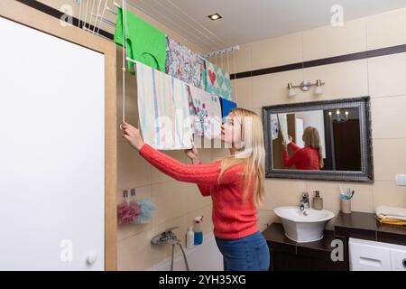 Une femme accroche le linge dans une salle de bain moderne qui met en valeur une esthétique de design épuré Banque D'Images