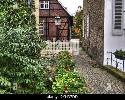 Une ruelle pavée mène devant une maison à colombages, bordée de fleurs et de lanternes, nottuln, muensterland, allemagne Banque D'Images