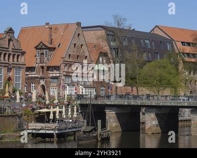 De charmantes maisons à colombages bordent une rivière, tandis qu'un pont mène à un quartier historique, lueneburg, en allemagne Banque D'Images