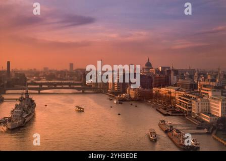 Années 1980 Londres Retro Thames View Vintage Old Historic Archive vue d'ensemble de la ville au spectaculaire coucher de soleil rouge avec la Tamise vue du haut de Tower Bridge avec le HMS Belfast au premier plan, les bateaux de croisière sur la Tamise et les gratte-ciel de Londres, y compris la cathédrale Pauls et BT Tower derrière Londres Royaume-Uni Banque D'Images