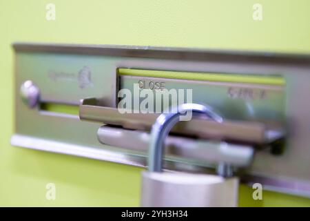 Gros plan d'un cadenas fixant un loquet coulissant sur une porte verte d'unité de rangement pour plus de sécurité. Banque D'Images