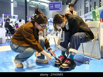 Shanghai. 9 novembre 2024. Un exposant aide un visiteur à essayer une paire de chaussures intelligentes à la section spéciale incubation pendant la 7ème China International Import Expo (CIIE) à Shanghai, dans l'est de la Chine, le 9 novembre 2024. Avec le thème « franchir les frontières, incuber les forces innovantes et diriger les technologies du futur », la section spéciale incubation du 7e CIIE vise à offrir aux incubateurs technologiques l'opportunité d'explorer conjointement les voies de l'innovation. Crédit : Wang Yijie/Xinhua/Alamy Live News Banque D'Images