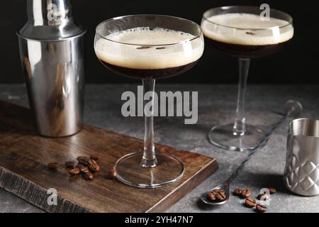 Verres de délicieux espresso martini, shaker et grains de café sur la table à texture foncée, gros plan Banque D'Images