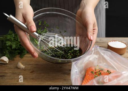 Femme avec marinade de soja et filet de saumon dans un sac en plastique à la table en bois, gros plan Banque D'Images