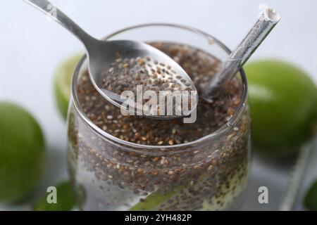 Verre de boisson avec des graines de chia et citron vert sur la table blanche, gros plan Banque D'Images