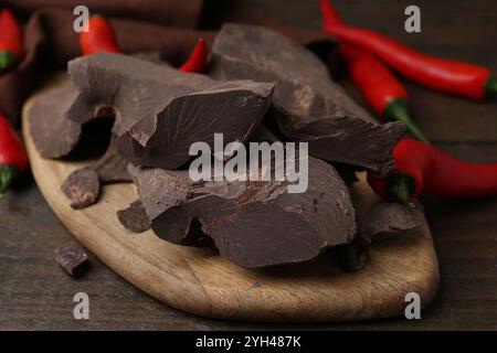 Morceaux de chocolat avec des piments sur une table en bois, gros plan Banque D'Images