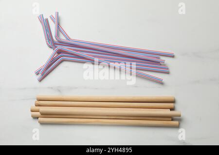 Pailles à boire en plastique et en bambou sur table en marbre blanc, pose à plat Banque D'Images