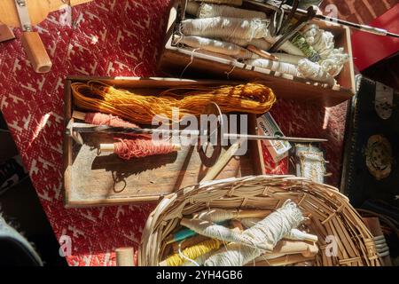 Trevi, Italie - 11 02 2024 - fournitures de tissage artisanal dans un studio rustique avec des bobines de fil colorées outils en bois et panier en osier illuminé par Natural Banque D'Images