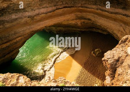 Une vue de haut en bas de la grotte de Benagil au Portugal, révélant des eaux turquoises et une plage de sable à travers le puits de lumière ouvert massif par une journée ensoleillée. Banque D'Images