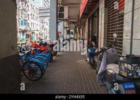 Scène de rue animée avec vélos et scooters à Shanghai, Chine Banque D'Images