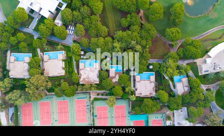 Vue aérienne des villas de luxe avec piscines privées et courts de tennis entourés d'une verdure luxuriante, idéal pour une escapade reposante. Banque D'Images