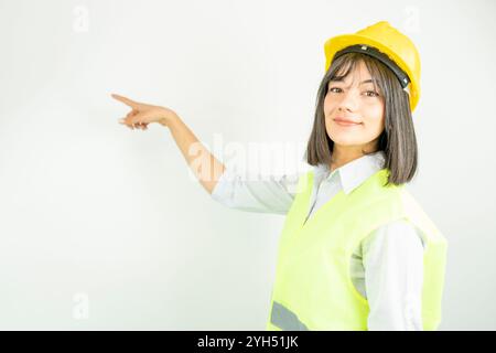Femme architecte ou ingénieur portant un casque industriel pointant avec le doigt. Portrait féminin isolé. Banque D'Images