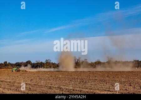 Un tracteur John Deere cultive un champ et soulève des nuages de poussière à Stanislaus California USA Banque D'Images