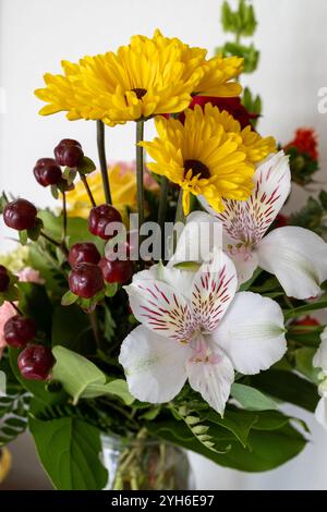 Vue macro abstraite de fleurs en fleurs dans un arrangement de fleuriste d'intérieur, mettant en vedette des chrysanthèmes jaunes et des lis péruviens Banque D'Images