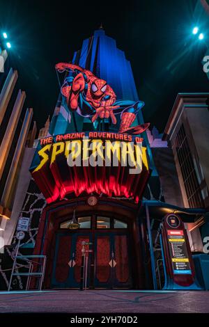 Une vue dynamique de l'entrée de l'attraction Amazing Adventures of Spider-Man, illuminée de lumières vibrantes et d'images de super-héros emblématiques. Banque D'Images