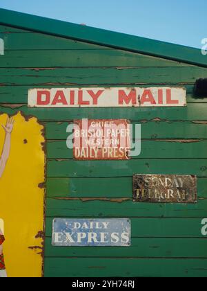 Des panneaux d'émail vintage annoncent Daily Express, Daily mail, Sunday Telegraph et Western Daily Press (Bristol) sur un panneau vert à Bitton Station Banque D'Images