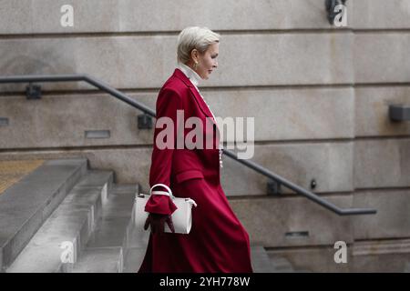 Femme élégante avec coupe courte dans Burgundy Coat Walks City Street, portant des vêtements à la mode pull à col roulé blanc, sac blanc. Confiant et C. Banque D'Images
