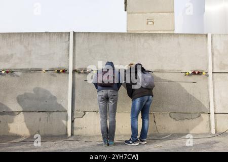 Deux visiteurs regardent à travers une brèche dans le mur lors de l'événement commémoratif central au Mémorial du mur de Berlin pour marquer le 35e anniversaire de la chute de Banque D'Images