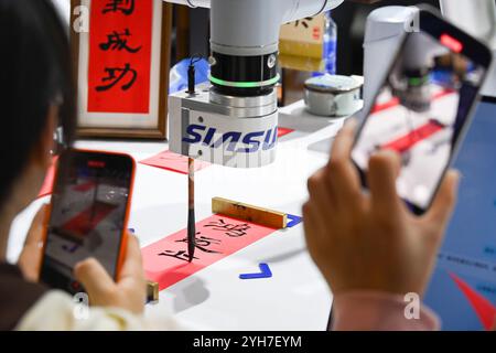 Shanghai. 9 novembre 2024. Les visiteurs prennent des photos d'un robot écrivant des calligraphies lors de la 7e exposition internationale d'importation de Chine (CIIE) à Shanghai, dans l'est de la Chine, le 9 novembre 2024. Le 7e CIIE s’est tenu ici du 5 au 10 novembre. De nombreux exposants ont offert diverses activités interactives pour que les visiteurs se familiarisent avec leurs produits et services. Crédit : Huang Xiaoyong/Xinhua/Alamy Live News Banque D'Images