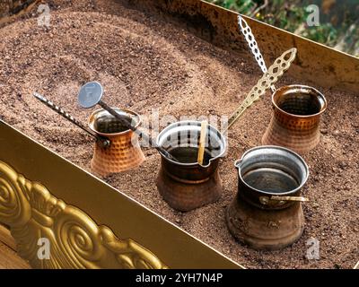 Préparation de café sur sable. Préparation de café de style turc avec turk de cuivre avec de longues poignées pour infuser du café en Géorgie. Banque D'Images